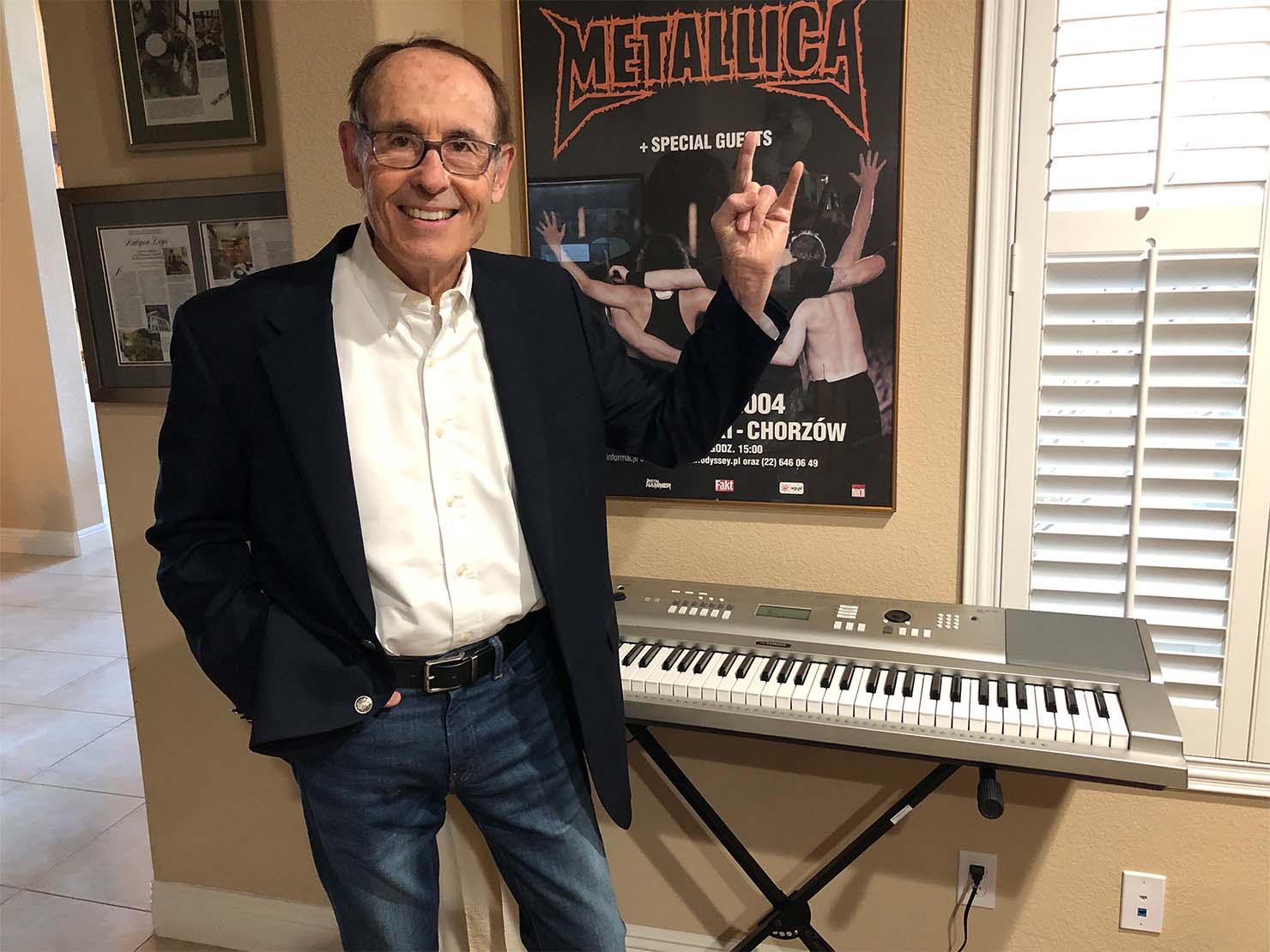 Metallicaのポスターの前で“メタルポーズ”をきめる、Phil Towle。