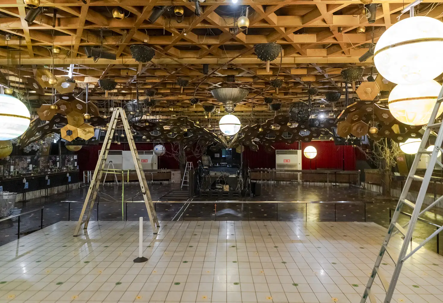 バズーカ型の照明もSTUDIO80時代に設置されたものと思われ、稼働時は上下に動きながら横回転をしていたそう。さらに、バズーカの周囲に垂れ下がっている金色の球体照明は、当時は手動で上下運動させていたと言われている<figcaption>フロア奥の壁側に沿ってある大理石の小上がりスペースもSTUDIO80の床がそのまま残っている。また、手前の白い格子状の床は、かつてテトリスのように光る床だったそうだが、大雨で浸水した際に使えなくなったという経緯があるという”>
<figcaption>バズーカ型の照明もSTUDIO80時代に設置されたものと思われ、稼働時は上下に動きながら横回転をしていたそう。さらに、バズーカの周囲に垂れ下がっている金色の球体照明は、当時は手動で上下運動させていたと言われている<figcaption>フロア奥の壁側に沿ってある大理石の小上がりスペースもSTUDIO80の床がそのまま残っている。また、手前の白い格子状の床は、かつてテトリスのように光る床だったそうだが、大雨で浸水した際に使えなくなったという経緯があるという</figcaption>
</figure>
<figure>
<img srcset=
