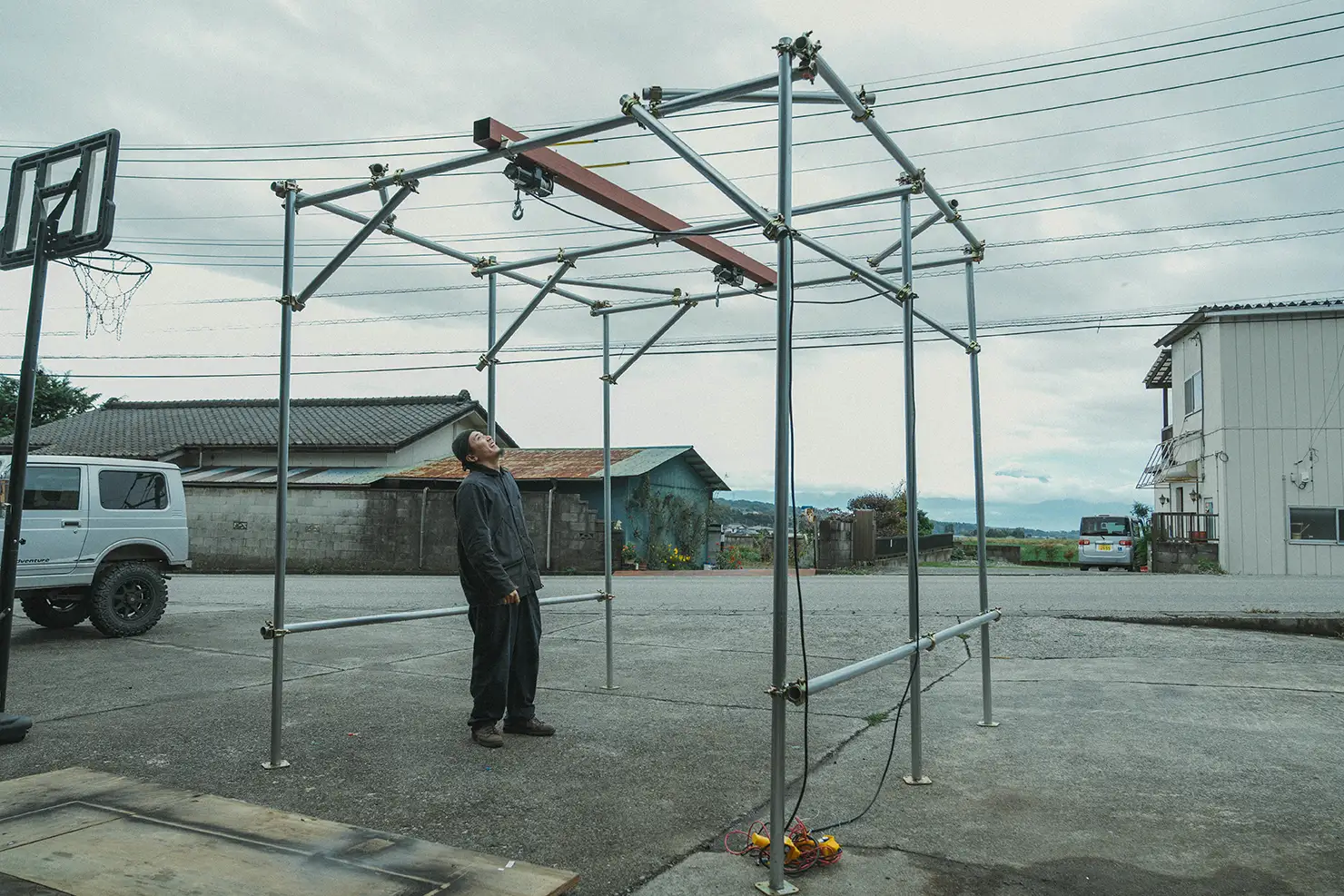 組み上げていた単管パイプのクレーンを見上げる村上さん。荷下ろしは想定していたようにはいかなかった